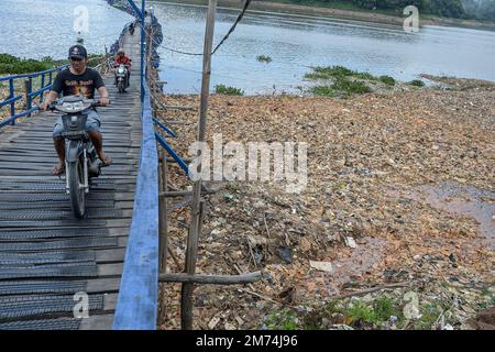 West Bandung Regency, Indonesien, 7. Januar 2023 - die Bewohner überqueren eine Brücke, unter der sich Müllhaufen am Ufer des Citarum River befinden. Stockfoto