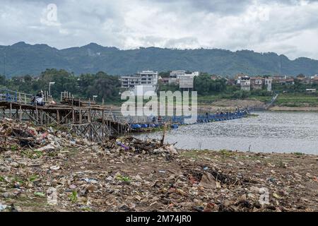 West Bandung Regency, Indonesien, 7. Januar 2023 - die Bewohner überqueren eine Brücke, unter der sich Müllhaufen am Ufer des Citarum River befinden. Stockfoto