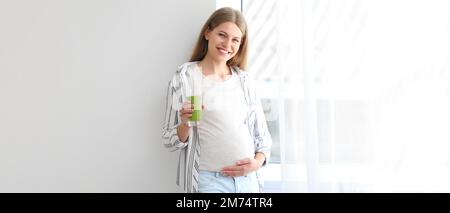 Schöne schwangere Frau trink Smoothie zu Hause Stockfoto