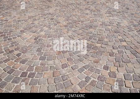 Kopfsteinpflastersteinpflasterstraße mit roten, braunen, gelben und grauen Felsen. Stockfoto