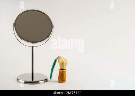 Lifestyle Waschraum-Rasierapparat mit drehbarem Standspiegel, natürlicher Haarbürste und Einwegrasierer isoliert auf weißem Hintergrund Stockfoto