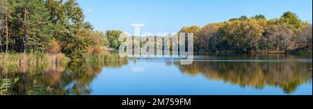 Herbstlandschaft an einem sonnigen Tag, Panorama eines Parks mit gelben Bäumen über einem See. Stockfoto