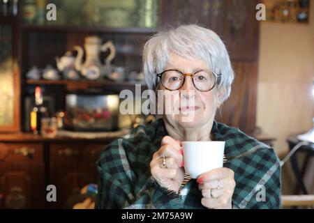 Seniorin mit einer Decke und warmem Getränk Stockfoto