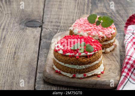 Hausgemachtes Dessert mit Schlagsahne und herzförmigen Streuseln auf einem Holztisch Stockfoto