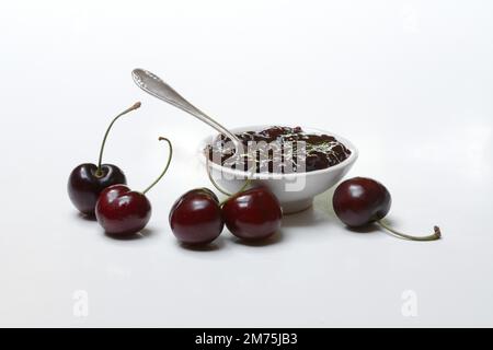 Kirschmarmelade in kleinen Schüsseln und schwarze Wildkirsche (Prunus avium) Stockfoto