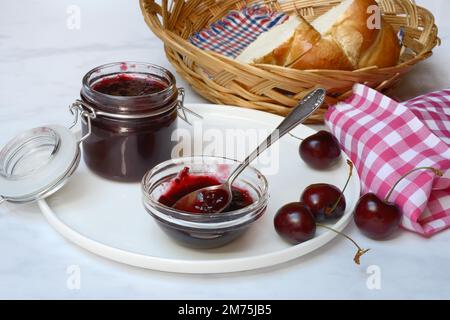 Kirschmarmelade in einer kleinen Schüssel mit Löffel, schwarze Kirschen Stockfoto