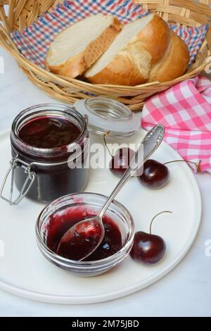 Kirschmarmelade in einer kleinen Schüssel mit Löffel, schwarze Kirschen Stockfoto