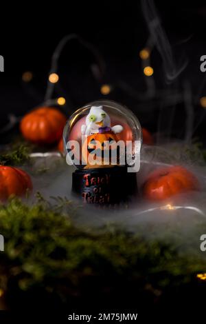 Eine Nahaufnahme eines Halloween-Kürbis-Schneeballs, umgeben von Harz-Kürbissen Stockfoto