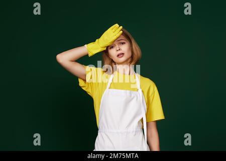 Müde Frau in gelben Handschuhen und sauberer Schürze Stockfoto