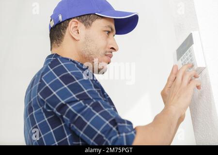 Ein Arbeiter, der den Alarm über die Tastatur einrichtet Stockfoto