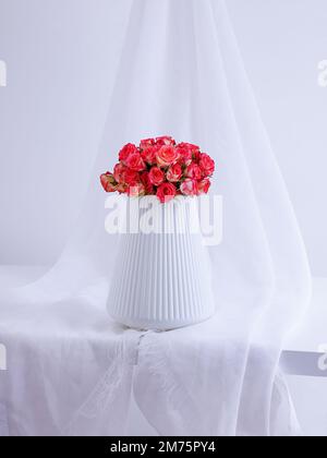 Ein wunderschöner Blick auf einen rosafarbenen Strauß in einer weißen Vase auf einem minimalistischen Hintergrund Stockfoto