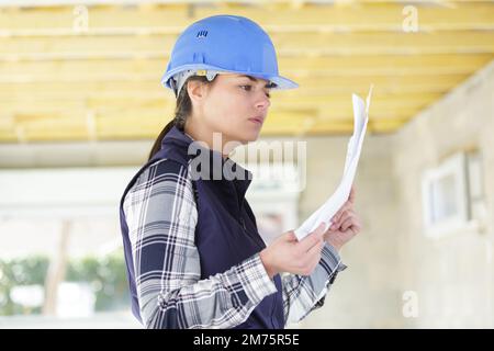 Architektin auf der Baustelle, die sich den Plan ansieht Stockfoto