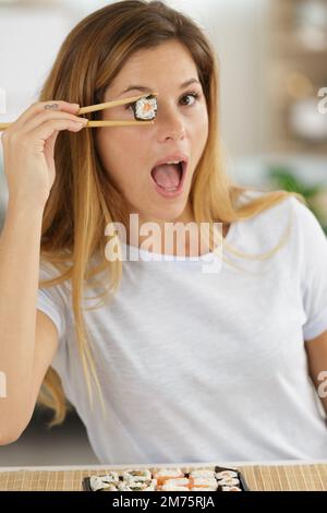 Eine junge Frau hält ein Sushi-Stück auf dem Auge Stockfoto