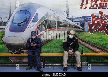 Zwei Mitarbeiter ruhen sich aus, nachdem sie einen CRH-Hochgeschwindigkeitszug auf der Wuhan-Hochgeschwindigkeitsbahnbasis überprüft haben. Am Samstag, dem ersten Tag des diesjährigen Frühjahrsfestes, werden voraussichtlich rund 6,3 Millionen Fahrten durch China unternommen, so der nationale Eisenbahnbetreiber China State Railway Group. China hat kürzlich sein epidemisches Kontrollmanagement optimiert, und auch epidemische Maßnahmen für Reisen wurden letzten Monat optimiert. Reisende brauchen keine negativen Nukleinsäuretests oder Gesundheitscodes mehr, sind nicht verpflichtet, sich Nukleinsäuretests oder Gesundheitsinspektionen bei der Ankunft zu unterziehen, und werden nicht Stockfoto