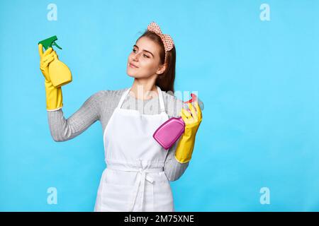 Frau mit Gummihandschuhen wählt zwischen zwei Reinigungsprodukten Stockfoto