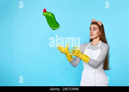 Eine Frau in Gummihandschuhen fängt eine fliegende Flasche Waschmittel Stockfoto