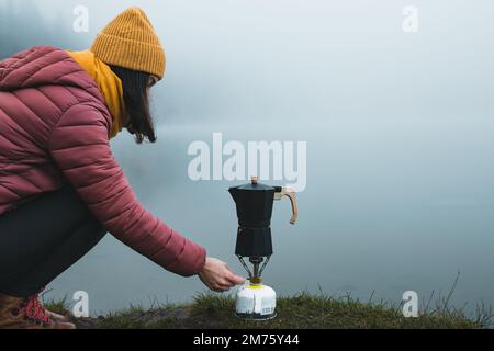 Wanderer, die Kaffee aus einer Moka-Kanne-Kaffeemaschine auf einem Camping-Gasherd zubereitet Stockfoto