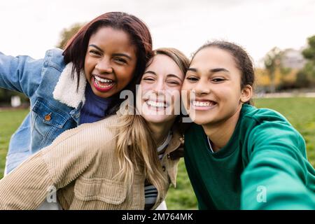 Multiethnische Gruppe von drei jungen Frauen, die ein Selfie machen und Spaß im Freien haben Stockfoto