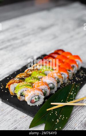 Gemischte japanische Sushi-Brötchen auf schwarzem Hintergrund. Stockfoto