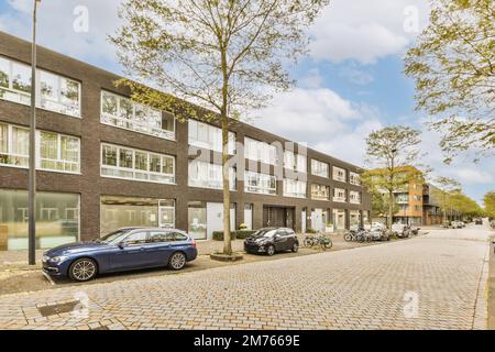 Eine Stadtstraße mit Autos, die an der Seite geparkt sind, und Gebäuden im Hintergrund, alle nach rechts ausgerichtet Stockfoto