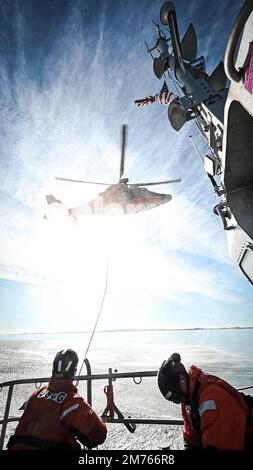 EIN US-AMERIKANISCHER Coast Guard Eurocopter MH-65 Dolphin Helicopter Crew von Air Station Savannah setzt während des Hubschraubertrainings im Hafen von Charleston, South Carolina, am 5. Januar 2023 eine Hebebühne aus. Die Evakuierung mit dem Hubschrauber ist eine schnellere Möglichkeit, Personen zu einer höheren Versorgungsstufe zu transportieren. (USA Air Force Photo von Staff Sgt. Joseph P. LeVeille) Stockfoto