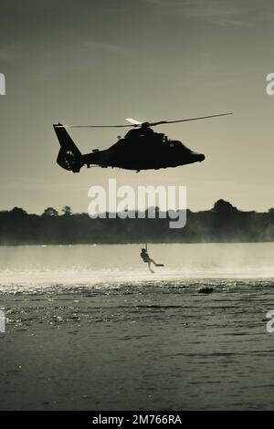 EIN US-AMERIKANISCHER Coast Guard Eurocopter MH-65 Dolphin Helicopter von Air Station Savannah schwebt während des Hubschraubertrainings im Hafen von Charleston, South Carolina, 5. Januar 2023. Die Besatzung trainiert routinemäßig für Hebevorrichtungen, falls eine medizinische Evakuierung in der Praxis erforderlich ist. (USA Air Force Photo von Staff Sgt. Joseph P. LeVeille) Stockfoto