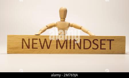 Auf der Holzoberfläche ist eine neue Denkweise geschrieben. Holzkonzept. Stockfoto
