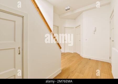Ein leerer Raum mit weißen Wänden und Holzfußboden die Tür befindet sich vor der Wand rechts