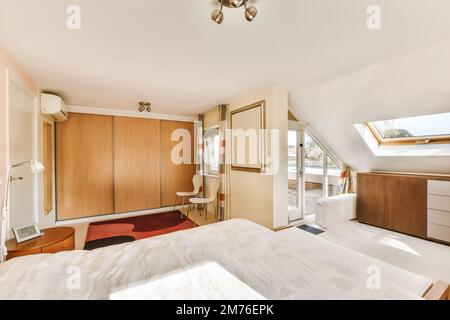 Ein Schlafzimmer mit einem Bett, Kommode und Spiegel im Eckbereich auf der linken Seite des Zimmers auf der rechten Seite Stockfoto