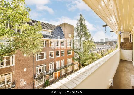 Ein Balkon mit Bäumen und Gebäuden im Hintergrund, der von einem Fenster auf der Dachterrasse eines Apartments mit Blick auf die Straße aufgenommen wurde Stockfoto