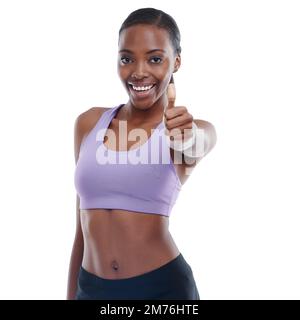 Positive Einstellung hilft mir, meine Ziele zu erreichen. Ein Porträt einer glücklichen jungen Frau in Sportbekleidung, die Daumen nach oben zeigt. Stockfoto