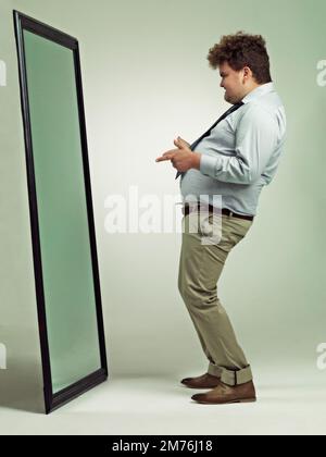 Wie geht's dir? Ein aufgeregter, übergewichtiger Mann feiert, während er in den Spiegel schaut. Stockfoto