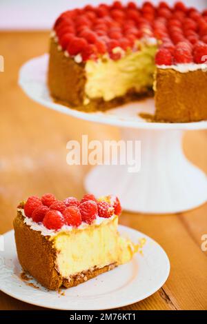 Nur ein Stück vom Himmel. Ein köstlicher Käsekuchen garniert mit Sahne und frischen Himbeeren. Stockfoto