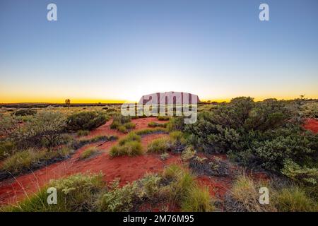 Outback, Australien - 12. November 2022: Sonnenaufgang am Majestic Uluru oder Ayers Rock im Northern Territory, Australien. Der rote Stein im Zentrum Stockfoto