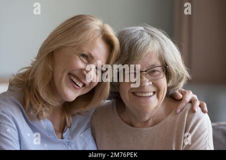 Fröhliche, reife Tochter, die ältere mutter mit Brille umarmt Stockfoto
