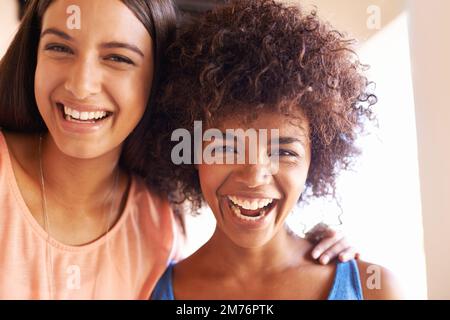 Alle lächeln, wenn Freunde abhängen. Zwei Freundinnen hängen zusammen. Stockfoto