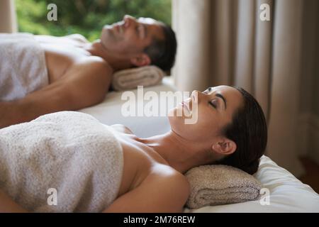 Schwelgen Sie in der einfachen Freude des Friedens. Ein reifes Paar, das sich auf seinen Massagetischen entspannt. Stockfoto