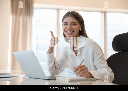 Eine Studentin lernt online ein Lächeln und zeigt eine „Daumen hoch“-Geste Stockfoto