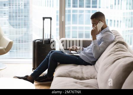 Ein Geschäftsmann telefoniert auf dem Sofa mit einem Laptop Stockfoto