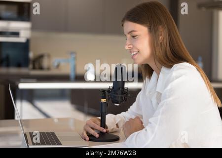 Frau verwendet Laptop, spricht in Mikrofon, leitet Internet-Streaming Stockfoto