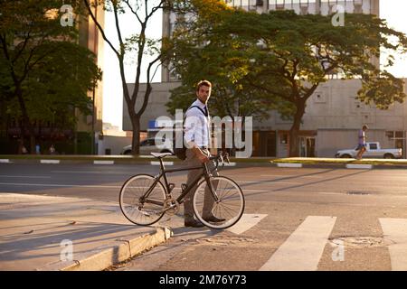 Auf dem grünen Weg umfahren. Ein Geschäftsmann, der mit seinem Fahrrad zur Arbeit pendelt. Stockfoto