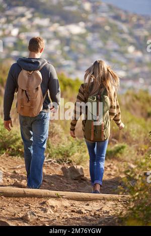 Ich mache es Seite an Seite. Rückansicht eines jungen Paares, das einen Wanderweg entlang geht. Stockfoto