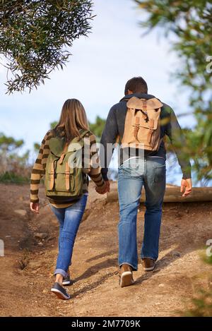 In der Natur zusammen. Rückansicht eines jungen Paares, das einen Wanderweg entlang geht. Stockfoto