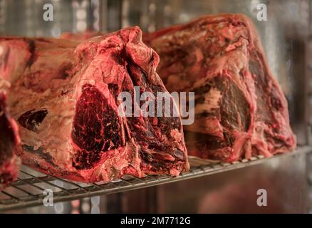 Klassisches ungeschnittenes Stück trockenes, gereiftes T-Bone Florentiner Steak von einer Chianina-Kuh auf einem Metzgertisch in einem Restaurant in Florenz, Italien Stockfoto