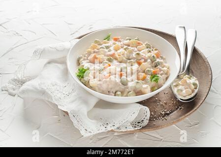 Schüssel mit russischem Salat olivier französischer Salat mit Gemüse und Ei mit Mayonnaise auf weißem Tisch Stockfoto
