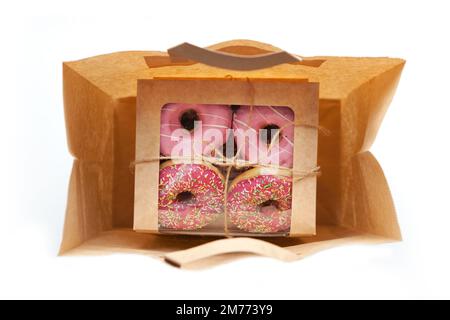 Pinkfarbene Donuts, verpackt in einer Craft-Tasche, isoliert auf weißem Hintergrund Stockfoto