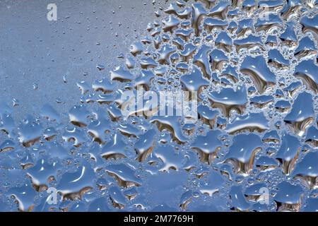 Makroabstrakter Texturhintergrund von Wassertropfen und Eisbildung auf einer inneren Glasscheibe mit natürlichem Design Stockfoto