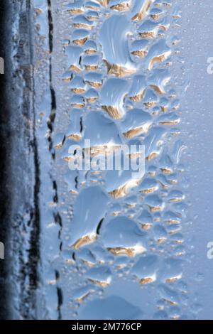 Makroabstrakter Texturhintergrund von Wassertropfen und Eisbildung auf einer inneren Glasscheibe mit natürlichem Design Stockfoto