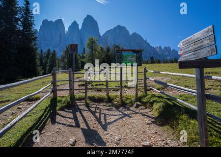 FUNES, ITALIEN, 1. SEPTEMBER 2021 - Wegweiser auf dem Pfad des Naturparks Puez-Odle mit der Odle-Gebirgsgruppe im Hintergrund, Bozen Stockfoto