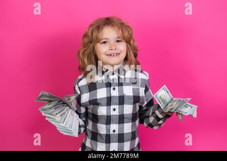 Kind mit vielen Dollar-Banknoten isoliert auf rosa rotem Studiohintergrund. Stockfoto